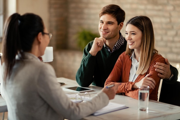 Foto gratuita giovane coppia sorridente che ha un incontro con il consulente finanziario in ufficio