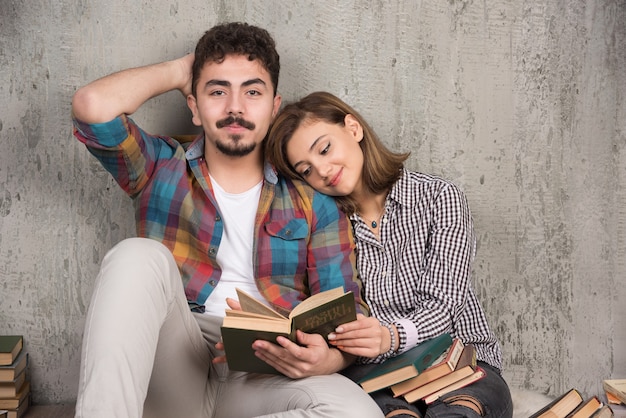 young smiling couple sitting on the floor with books