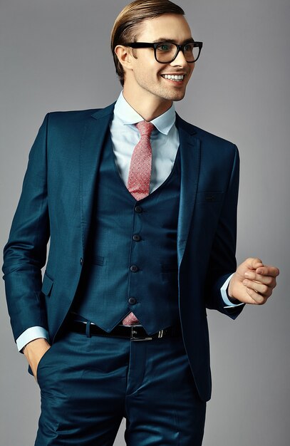 Young smiling elegant handsome  businessman male model in a suit and fashionable glasses, posing in studio