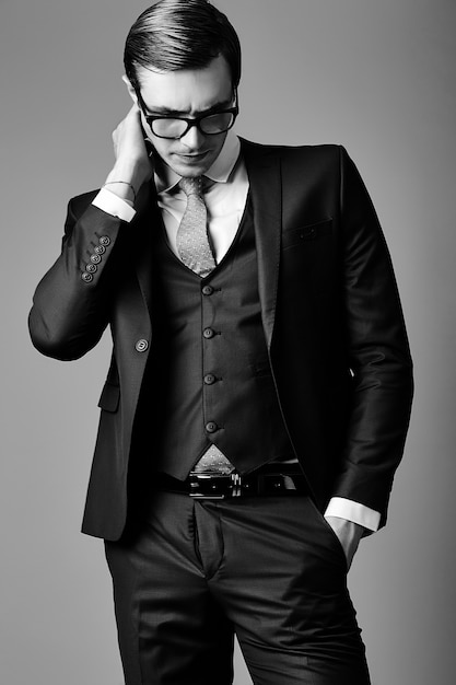 Молодой улыбающийся элегантный красивый бизнесмен мужской модели в костюме и модных очках, позирует в студии