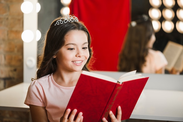 Young smiling girl reading book