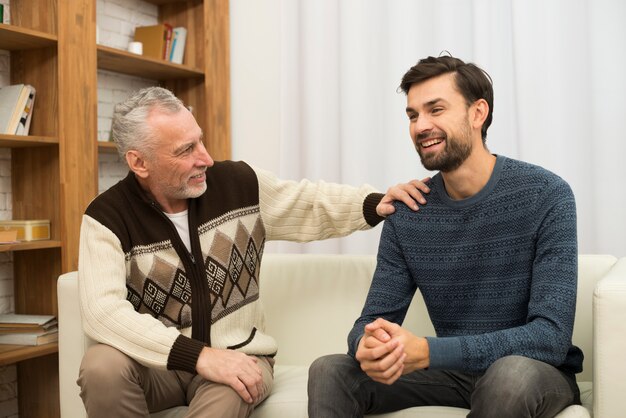 若い笑顔の男とソファの上の老人