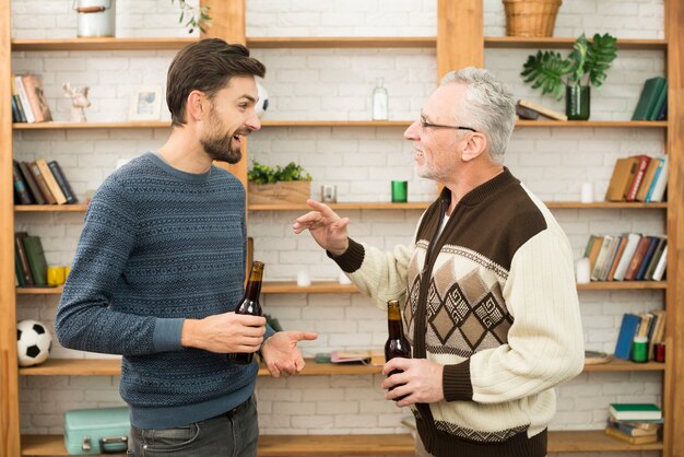 Young smiling guy talking with aged man with bottles