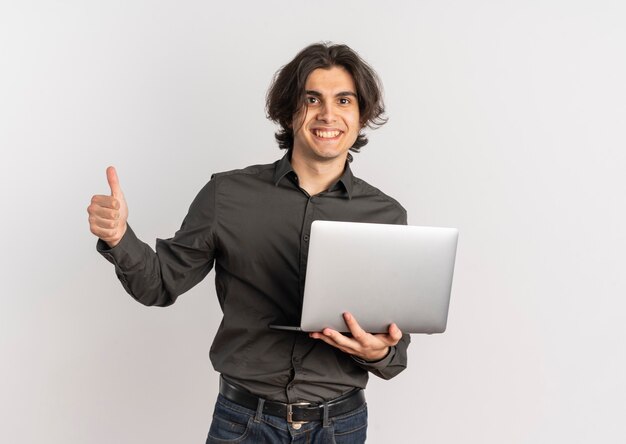 Young smiling handsome caucasian man holds laptop and thumbs up isolated on white background with copy space