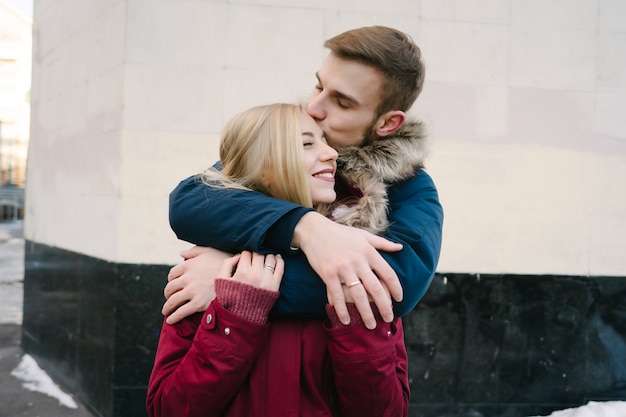 Молодая улыбающаяся счастливая европейская пара, обнимающая зимой