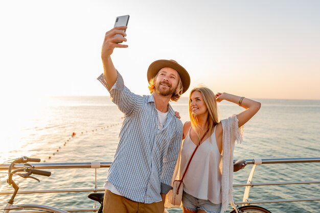 Young smiling happy man and woman traveling on bicycles taking selfie photo on phone camera