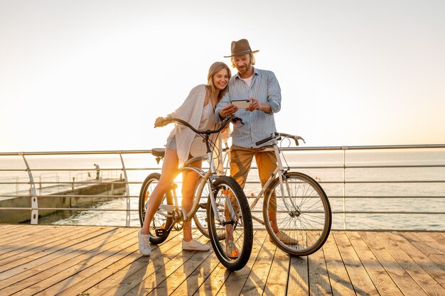 若い笑顔幸せな男と女がスマートフォンを使用して自転車で旅行