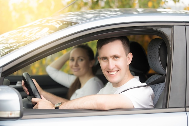 Young smiling man driving and woman sitting in the car