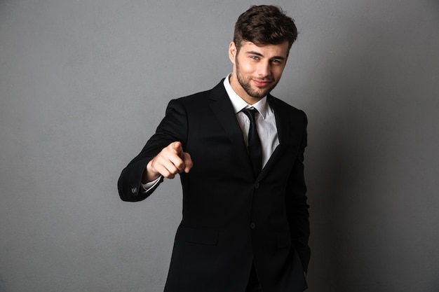 Young smiling man in formal wear pointing with finger on you, 