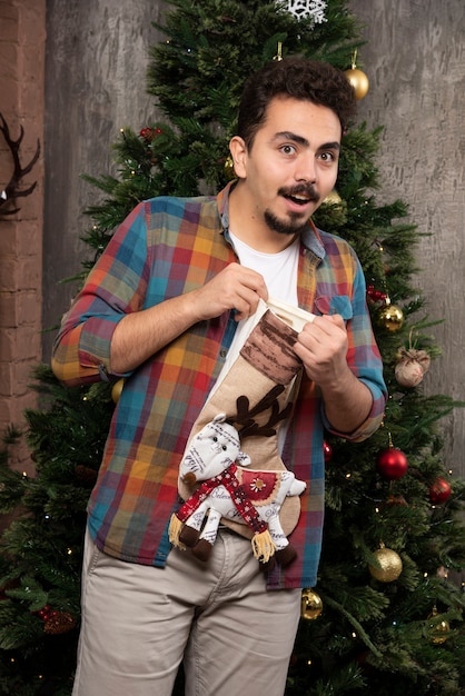 Young smiling man holding christmas socks.