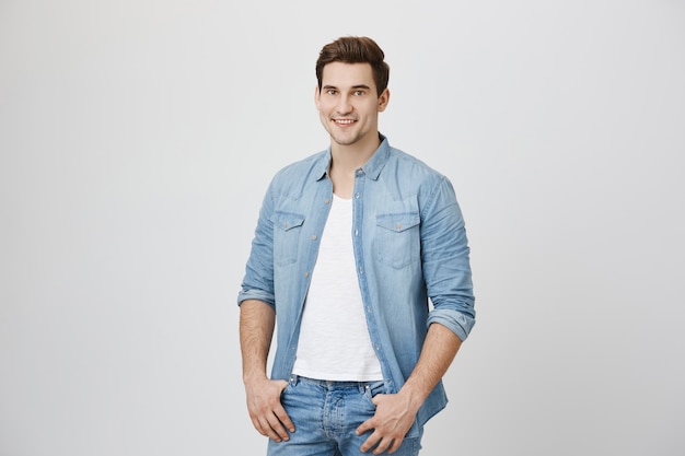 Young smiling man standing over white wall