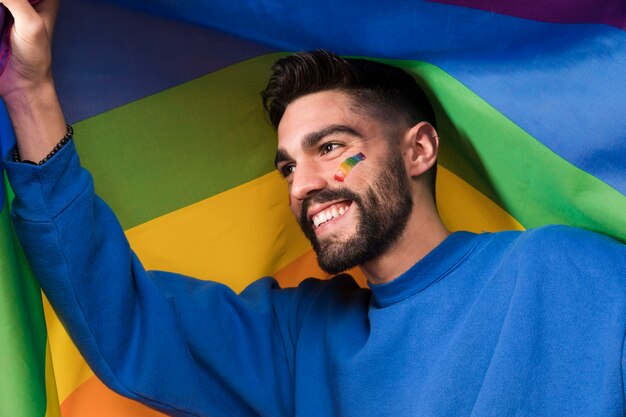 Young smiling man with LGBT rainbow flag