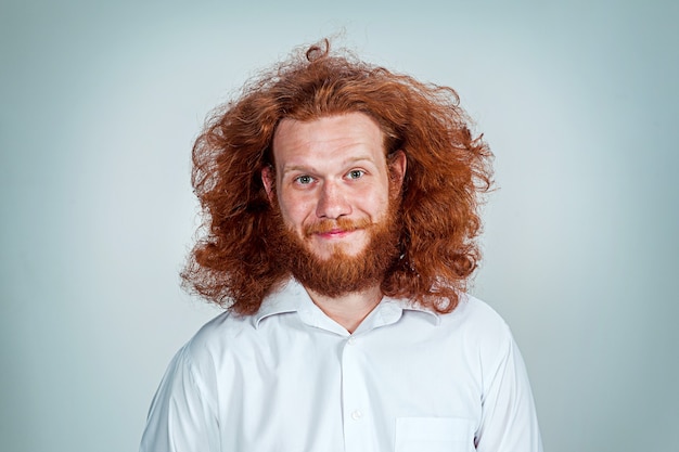 The young smiling man with long red hair looking at camera