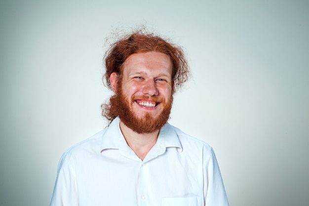 Free photo the young smiling man with long red hair looking at camera