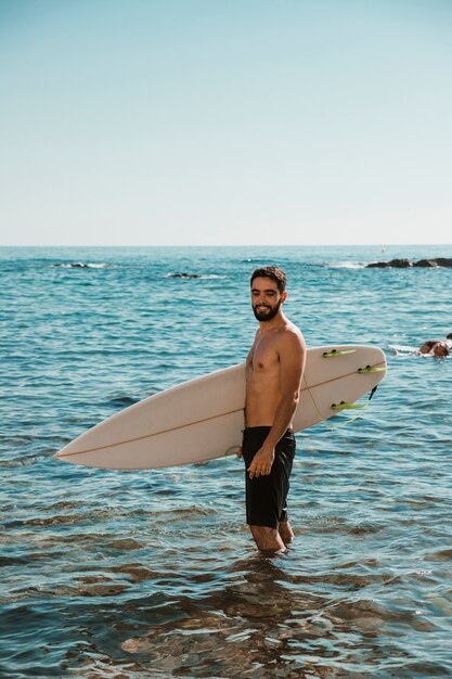 물에 해변 근처 서핑 보드와 함께 웃는 젊은이