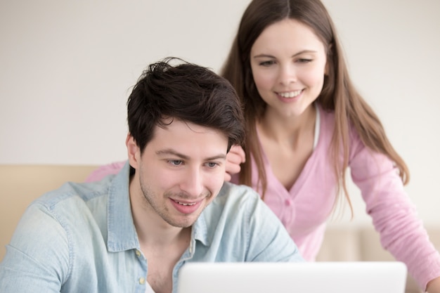 젊은 웃는 남자와 여자 실내 랩톱 컴퓨터를 사용하여