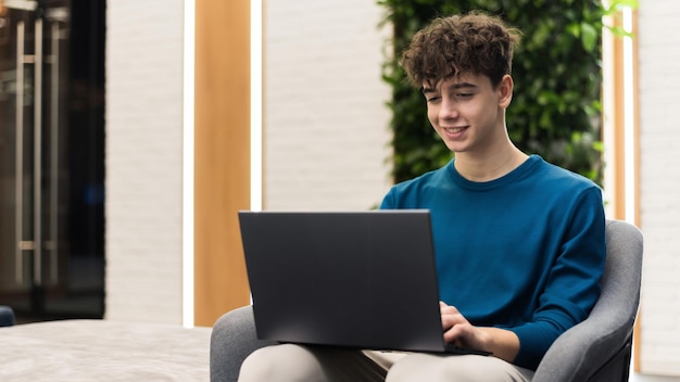 Young smiling man working with a laptop in an office