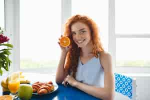 Free photo young smiling redhead lady holding orange