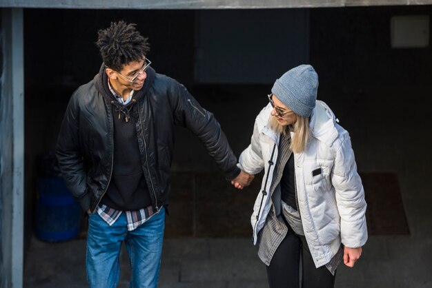 Young smiling stylish couple holding each other's hand making fun