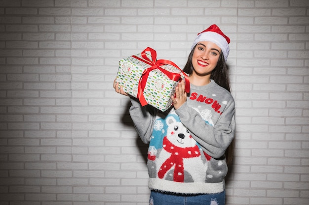 クリスマスの帽子とセーター、プレゼントボックスで若い笑顔の女性