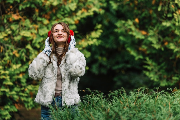 Молодая женщина улыбается в наушники в парке