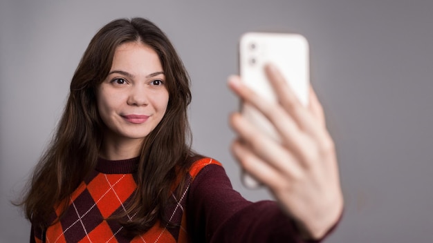 Free photo young smiling woman filming herself on the phone