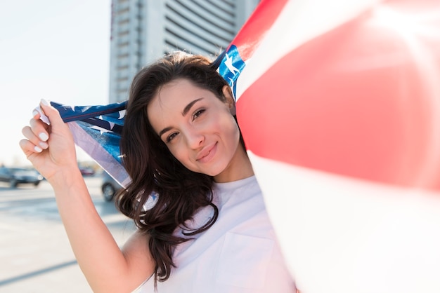Молодая усмехаясь женщина держа большой флаг США