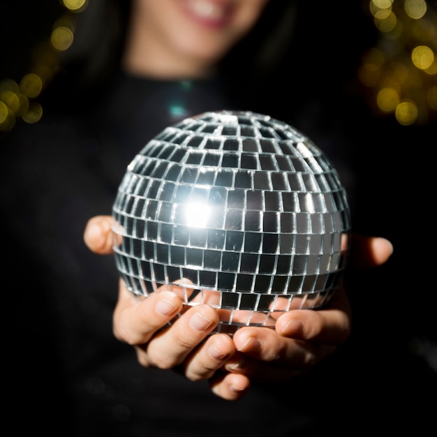 Free photo young smiling woman holding disco ball