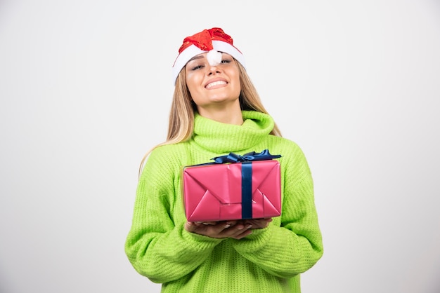 Молодая улыбающаяся женщина, держащая праздничный рождественский подарок.