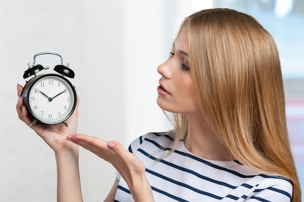 Young smiling woman holds black clock