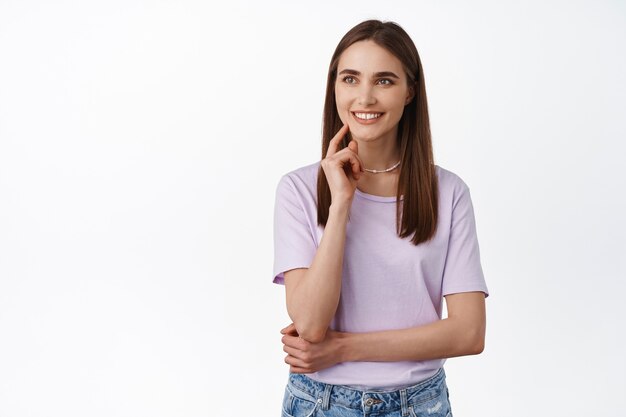 young smiling woman, looking with interest, determined, made her decision, staring left with pleased, satisfied face expression, standing on white