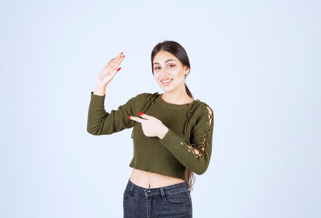 young smiling woman model showing stop sign and pointing away.