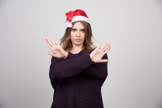 Foto gratuita giovane donna sorridente nel cappello di babbo natale che mostra il segnale di stop con le mani.