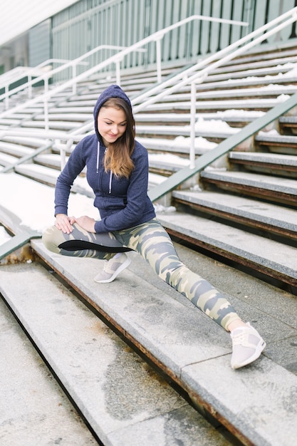 Young smiling woman stretching her leg on steps