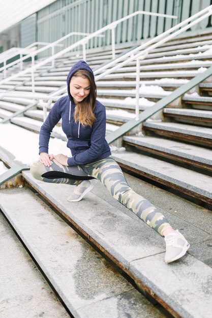 Young smiling woman stretching her leg on steps