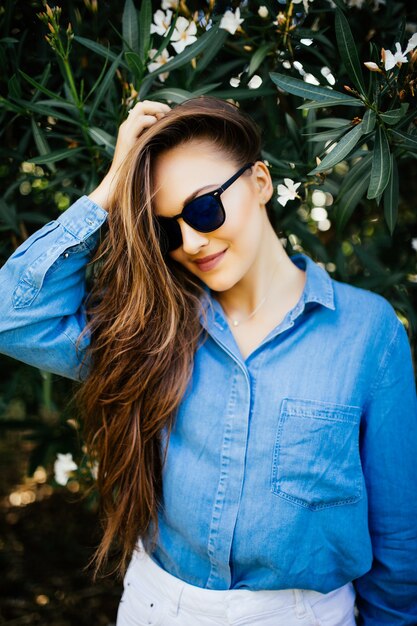 Young smiling woman in sunglasses on a green natural background. Woman portrait on green leaf background.