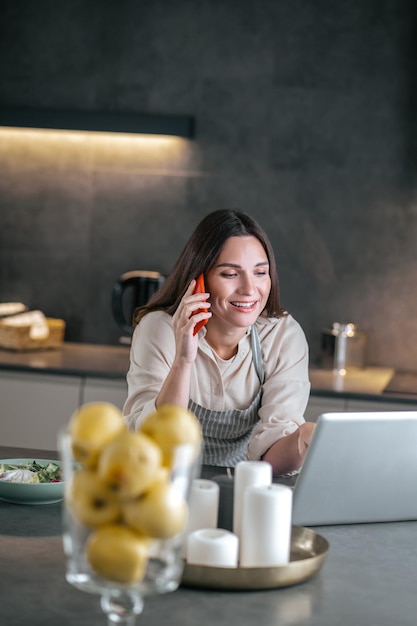 Young smiling woman talking on the phone in the kitchen