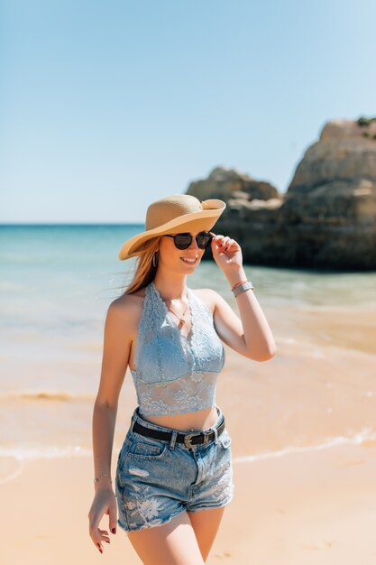 Young smiling woman on vacation with sun hat and glasses.