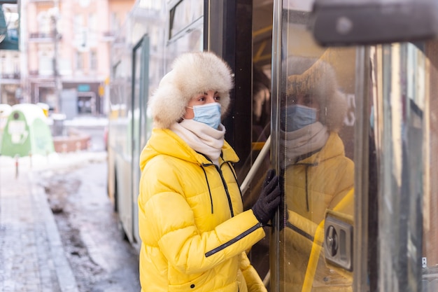 Young smiling woman walks into the bus on a winter day