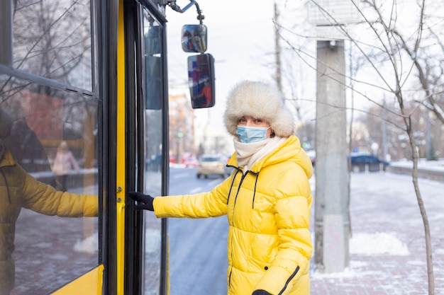 Бесплатное фото Молодая улыбающаяся женщина заходит в автобус в зимний день