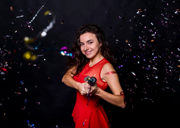 Free photo young smiling woman with popper between tossing confetti