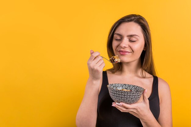 Young smiling woman with spoon and bowl of flakes