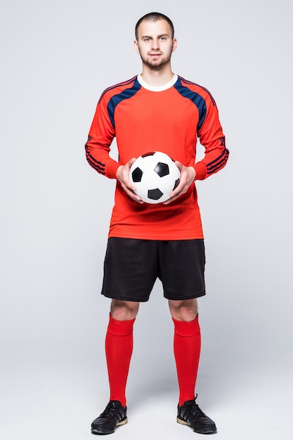 Free photo young soccer player with ball dressed in red jersey in front of white