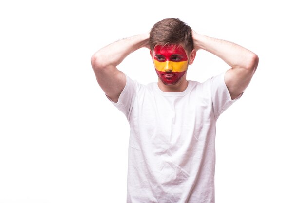 Young spanish man football fan with sad gesture isolated on white wall