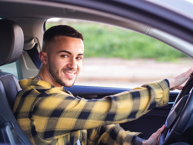 Foto gratuita giovane spagnolo sorridente e alla guida di un'auto