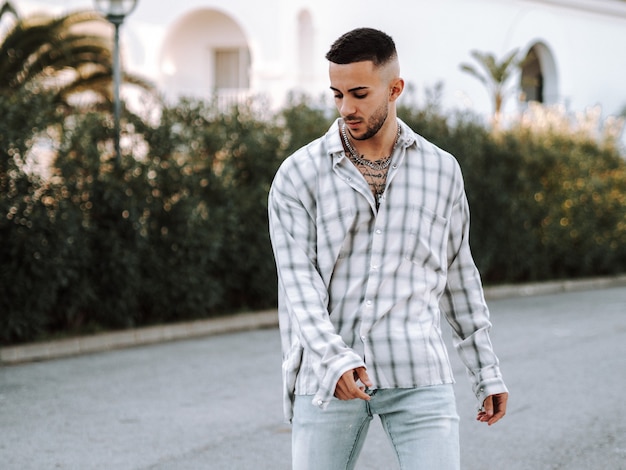 Free photo young spanish man with tattoos posing in the street