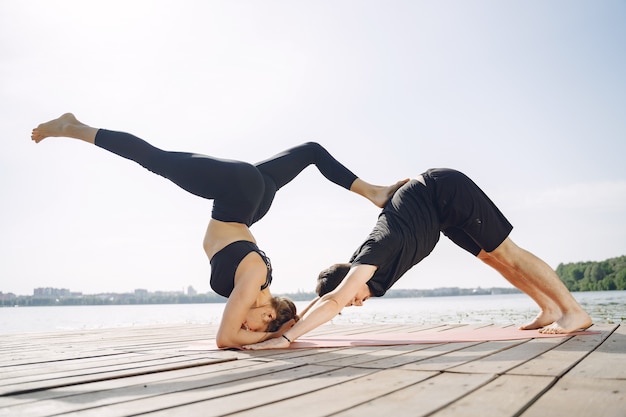 Young sportive couple doing yoga fitness . People by the water.