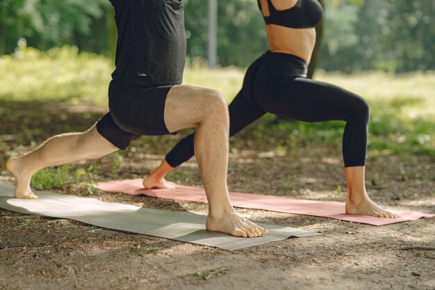 Young sportive couple doing yoga fitness . People in a summer park.