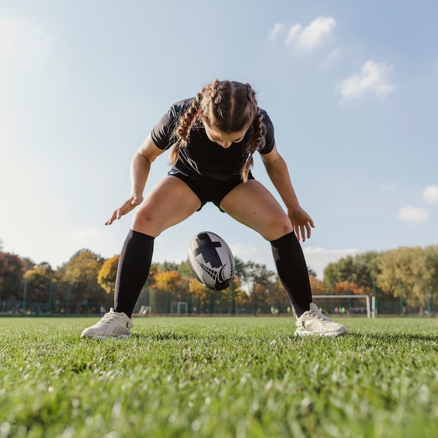 Foto gratuita giovane ragazza allegra che cade un pallone da rugby