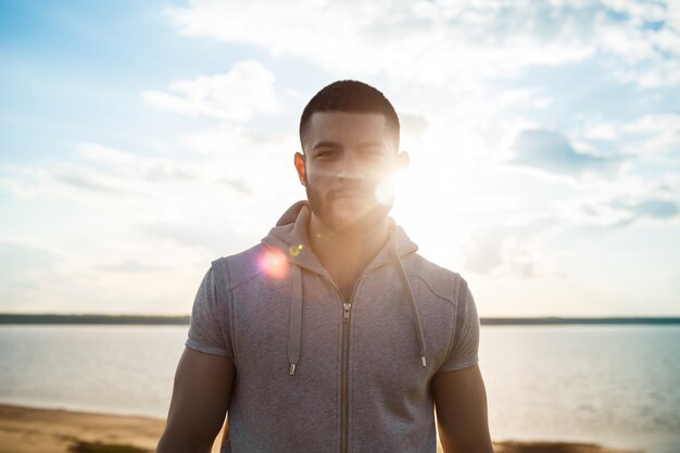 Young sportive man posing in field at sunrise.